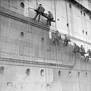 Painters are at work on the huge task of painting the hull of the Cunard White Star