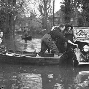 Rescue comes by boat to the occupants of a marooned car in a flooded road at Maidenhead