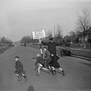 Road attendant from Kent County Council, holding a sign, helps children in St Mary