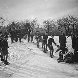 Schoolboys sliding on the snow on a path in Orpington, Kent. 1937