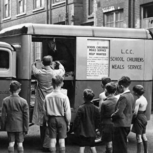 Schoolboys watch one of their meals-on-wheels arriving. Every day in various cooking centres