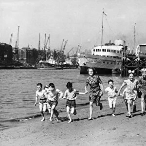 Summer at last, children running on the beach by the Tower of London. The pleasure