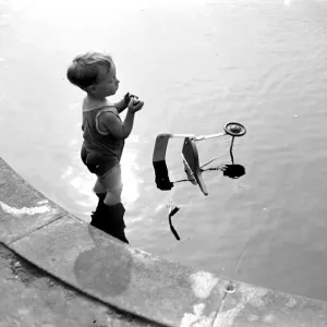 Toddler and his trike in the water. 1933