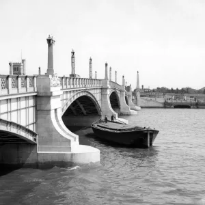 Watermen steering their barge underneath Lambeth Bridge, London