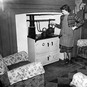 A woman boils to kettle for her cup of tea, in the main room of her cottage. The