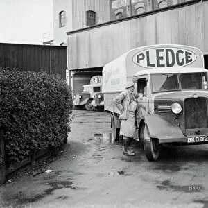 A worker chats to the driver of a loaded Bedford truck belonging to Pledge & Son Ltd