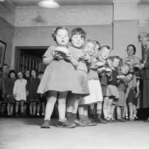 Young children receive their buns from the Guy Fawkes Charity. 1935