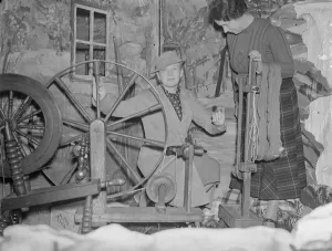 Ann Harding tries spinning wheel at Scottish textile show in London. Miss Ann Harding
