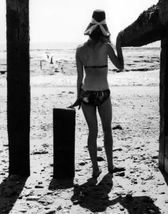 Seaside Prints: Ann Powys - A woman in the 1960s in a bikini on the beach wearing a straw sun hat