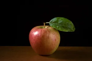 Renaissance Prints: Apple with leaf on wooden surface against black background credit: Marie-Louise