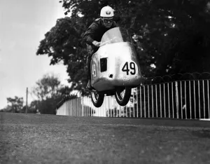 Motorsport TT Race Prints: Bob McIntyres Norton takes off as he comes over Ballaugh Bridge during the International