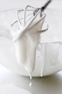 Bowl of white icing with dripping balloon whisk credit: Marie-Louise Avery / thePictureKitchen