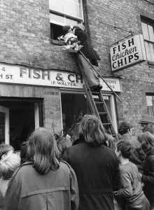 Marriage Prints: The bridegroom climbs a ladder to kiss his bride at the window above a fish and chip shop