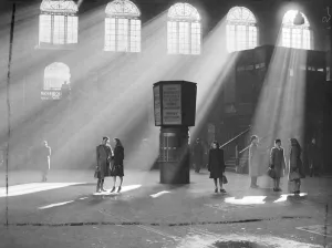 Bright sunshine streams through the glass roof to pierce the gloom at Liverpool Street