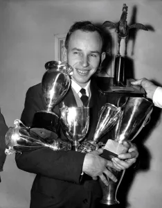 Award Prints: British Motorcycle World Champion John Surtees has both arms full of trophies already