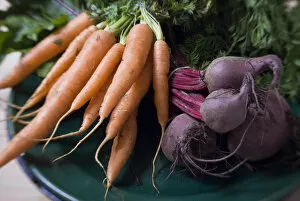 Vegetable Collection: Bunches of fresh carrots and beetroot on dark green platter credit: Marie-Louise