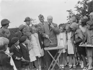 Canon Rs Greaves shows of a cake to children in Chislehurst, Kent
