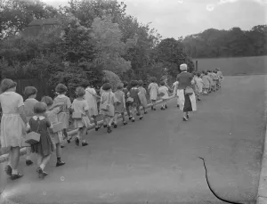 Girl Prints: Children out with a nurse equipped with their gasmasks in Sidcup, Kent. 1939