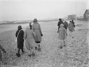 Children playing on the shingle beach at Dungeness. They use beach shoes to walk