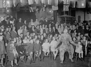 Hall Prints: Children watch enthralled as a clown balances an umbrella on his nose at the Territorial