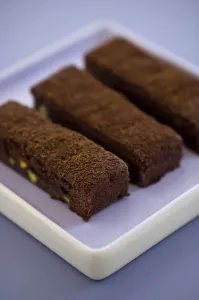Sweet Prints: Three chocolate tray bake slices dusted with cocoa powder on square mauve plate credit