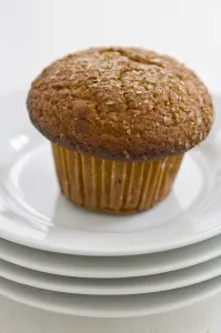 Cinnamon bran muffin on stack of white plates with cup of black coffee credit