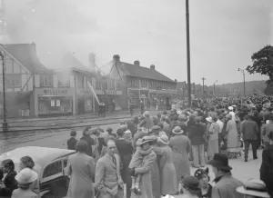 Firemen Prints: Crowds watch as firemen attempt to put out fires in a parade of shops in Welling, Kent