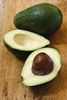 Whole and cut fresh avocado pear on wooden background credit: Marie-Louise Avery