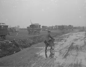 A cyclist negotiates a very muddy road with gypsy caravans parked on Belvedere marshes