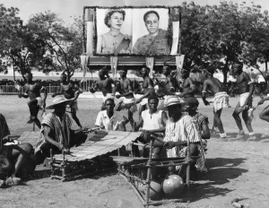 Dancers leap and jump round the men playing the native idea of a xylophone