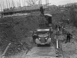 Digger clears the land and puts soil into the back of Bedford truck on the site of