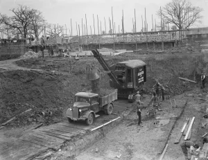 Digger clears the land and puts soil into the back of Bedford truck on the site of
