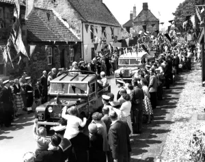Driving through the streets in a landrover the Queen smiles at the crowds on either side