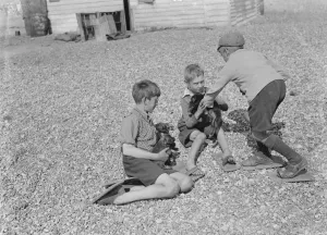 Pebbles Prints: Dungeness beach. Boys with puppies. They use beach shoes to walk over the stones