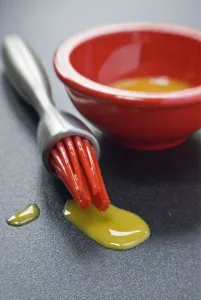 Bowl Prints: Egg yolk in small red bowl and dripping off red silicone bristles of modern pastry