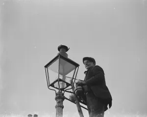 Lampost Prints: An elderly man lighting an oil street lamp in Hokenden, Kent. 1939