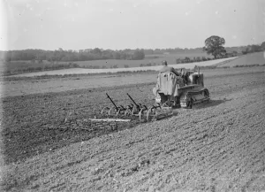 Machinery Prints: A farmer and his tank track tractor cultivates a field. 1935