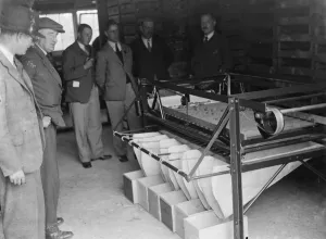 Farmers Prints: Farmers looking at machinery for fruit grading at the fruit farm. 1935