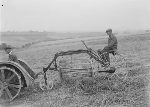 Farmers using a new tractor drawn haymaking machine on a field in Farningham, Kent