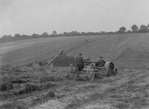 Farmers using a new tractor drawn haymaking machine on a field in Farningham, Kent