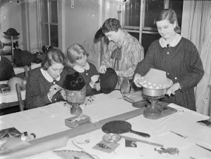 Feminine fingers taught intricacies of a fashion. Girl students at work in the millinery