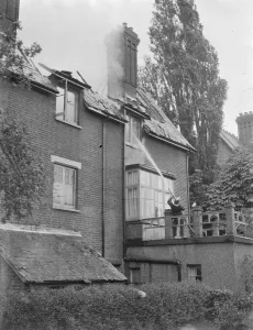 Firemen respond to a house fire in Chislehurst, Kent. A fireman hoses water into
