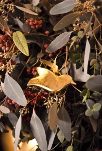 Berry Prints: Detail of fireplace decorated for Christmas with massed mixed foliage and golden