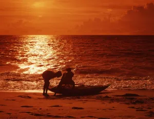 Sunset Prints: Fishermen pulling in their boat, on a beach neara Welligama