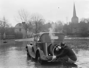 Kent Prints: Flooding in Eynsford, Kent. A motorist uses a hose to extend the exhaust of his