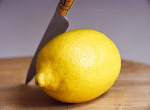 Whole fresh lemon with knife on cutting board credit: Marie-Louise Avery / thePictureKitchen