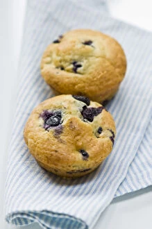 Berries Collection: Freshly baked blueberry muffin on blue striped napkin. credit: Marie-Louise Avery