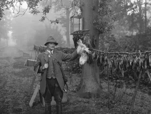Gamekeeper, Mr Barrett, poses with a hawk he has killed. 1936 Gamekeeper, Mr Barrett, poses with a hawk he has killed. 1936