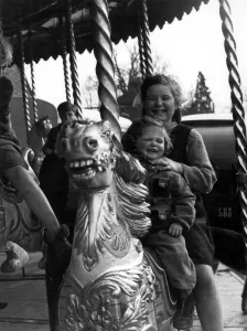 Fair Prints: Two girls sitting on a horse on the merry-go-round at the Funfair