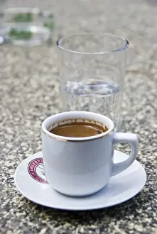 Glass Prints: Greek coffee and glass of water on table of restaurant in Cyprus hills. credit